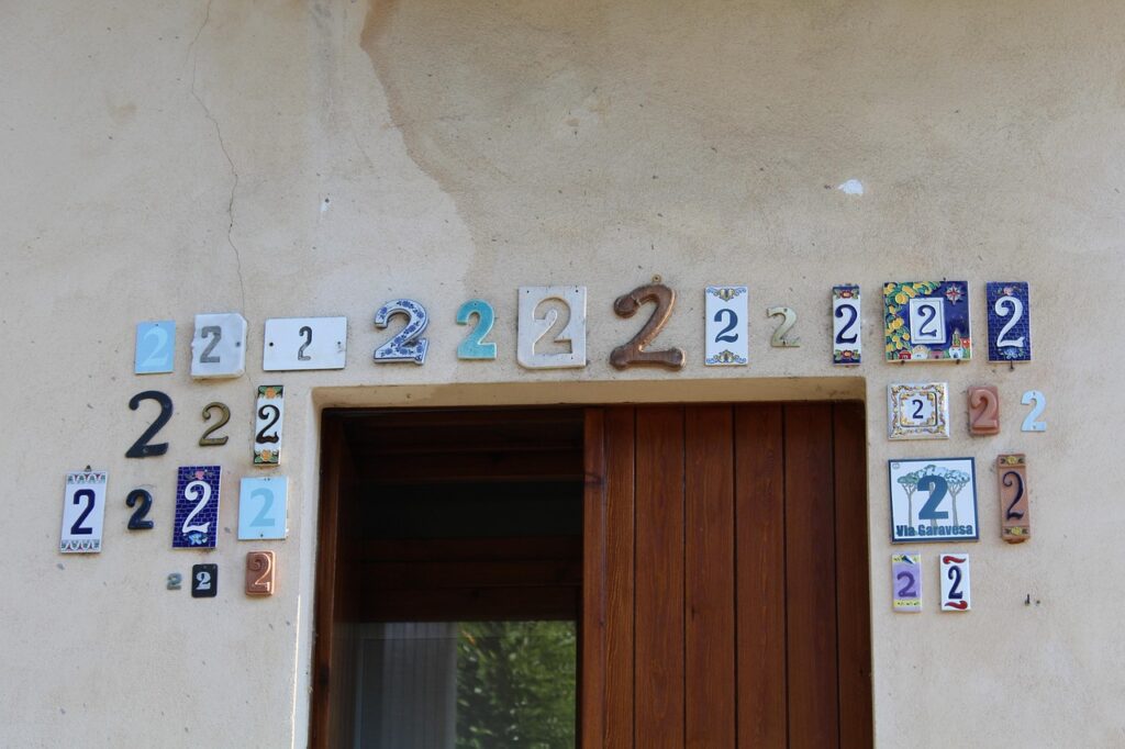 Façade d’une maison décorée de nombreuses plaques avec le chiffre 2 au-dessus de la porte d’entrée.