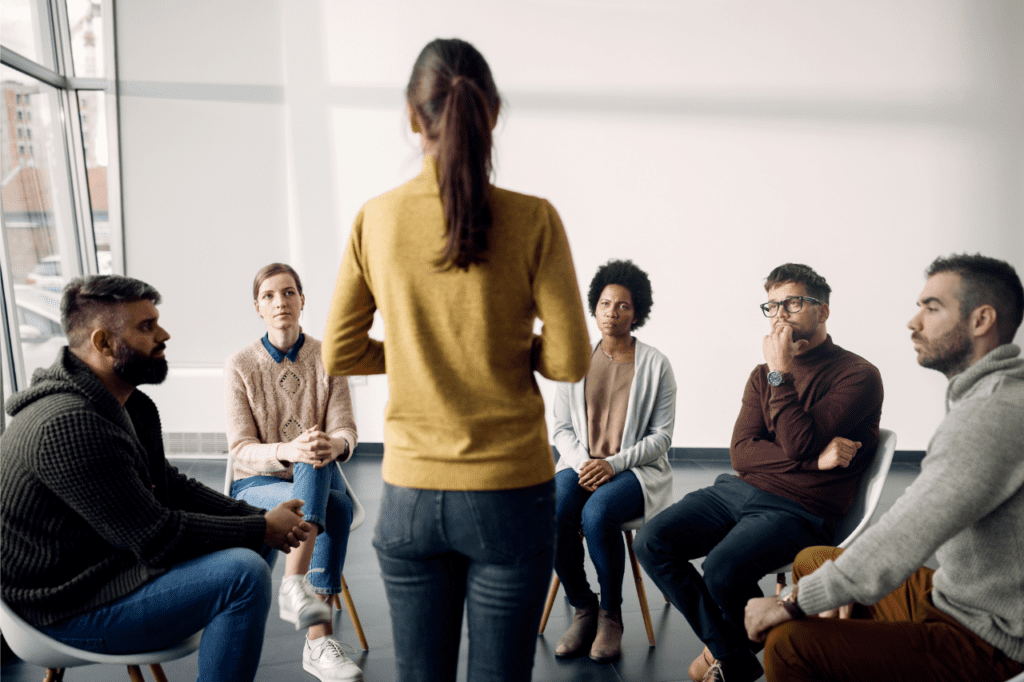 Groupe de personnes assises en cercle écoutant une intervenante, symbole d’échange, de clarification et de mise en mouvement relationnelle en février 2026.