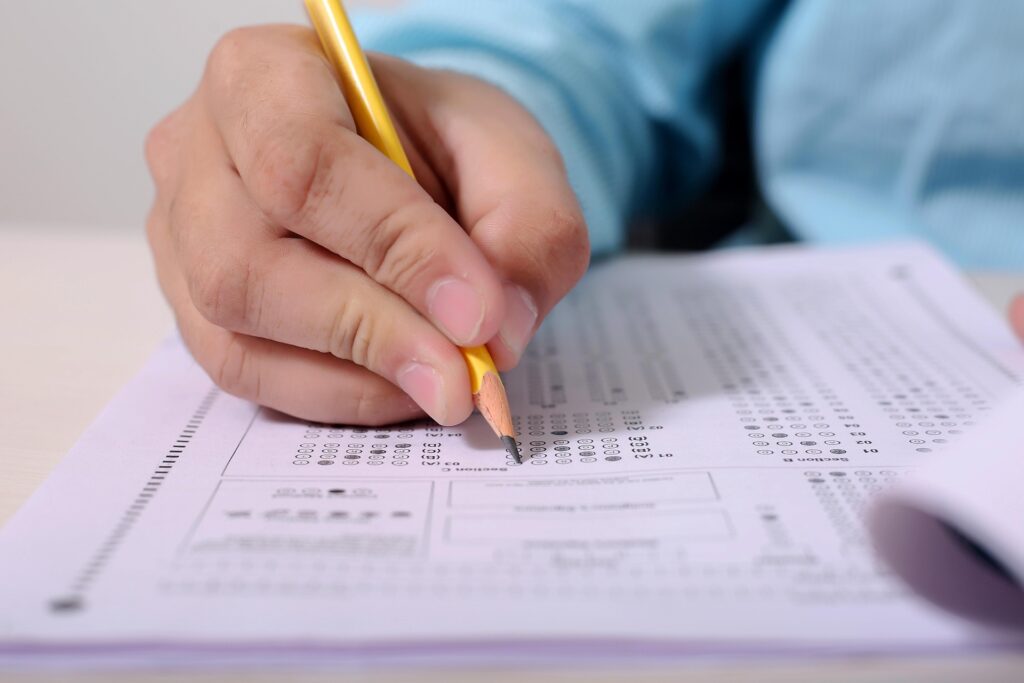 Main tenant un crayon au-dessus d’un questionnaire, illustrant un exercice de calcul, d’analyse et de réflexion en numérologie.