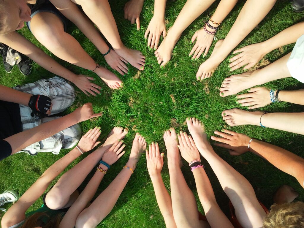Groupe d’enfants assis en cercle dans l’herbe, illustrant l’énergie du 2 en numérologie, la relation, la coopération et la capacité à créer du lien.