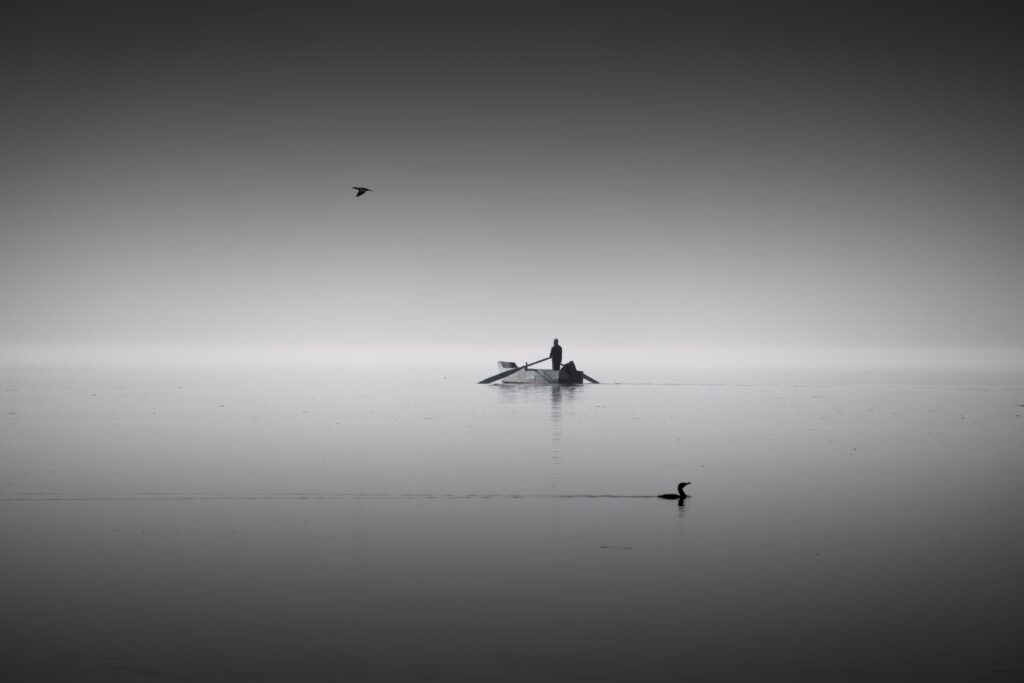 Silhouette solitaire dans une barque sur lac brumeux en noir et blanc symbole de silence et d'introspection numérologie juin 2026